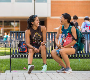 students talking on a bench on campus